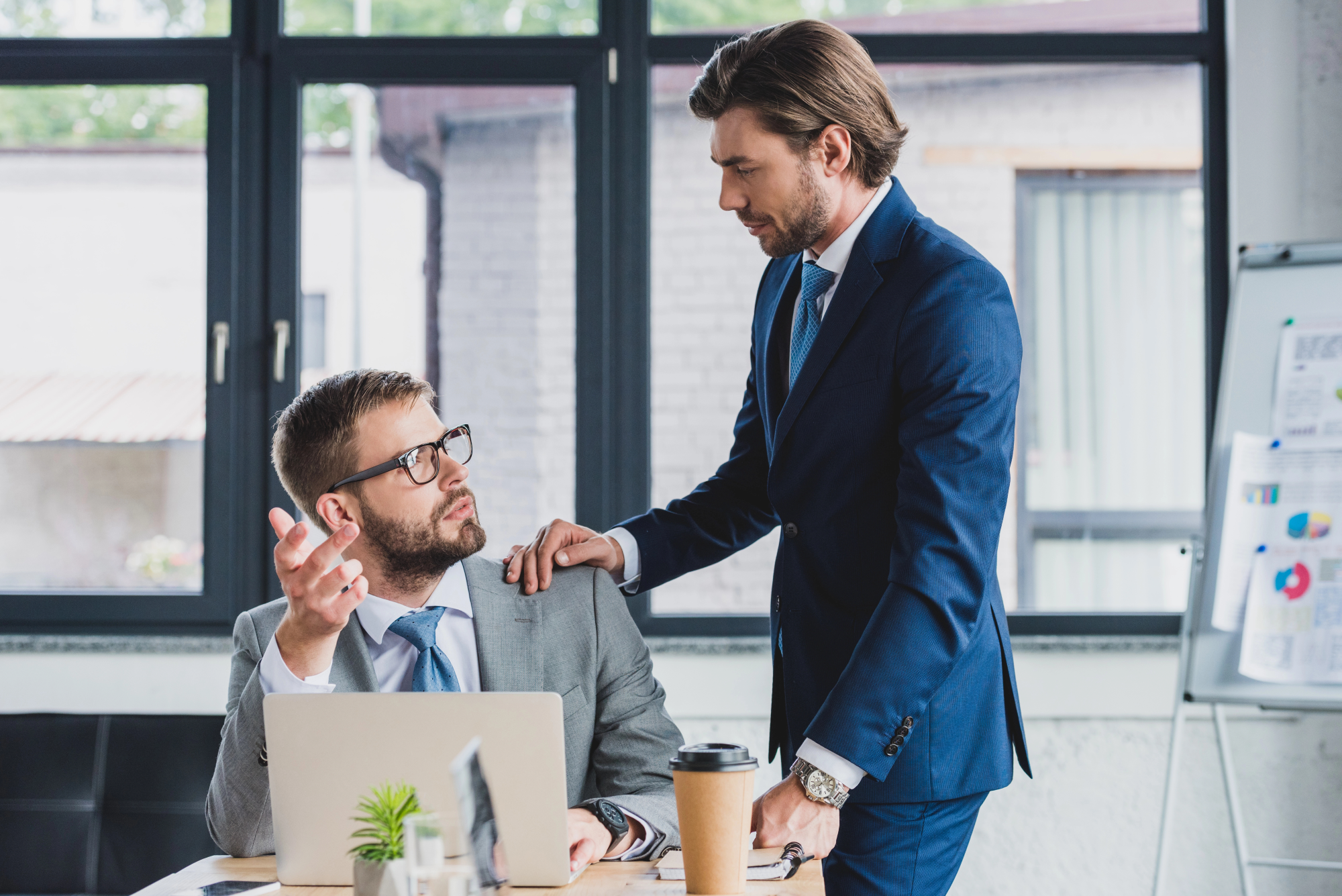 Serious young businessmen looking at each other and discussing project in office