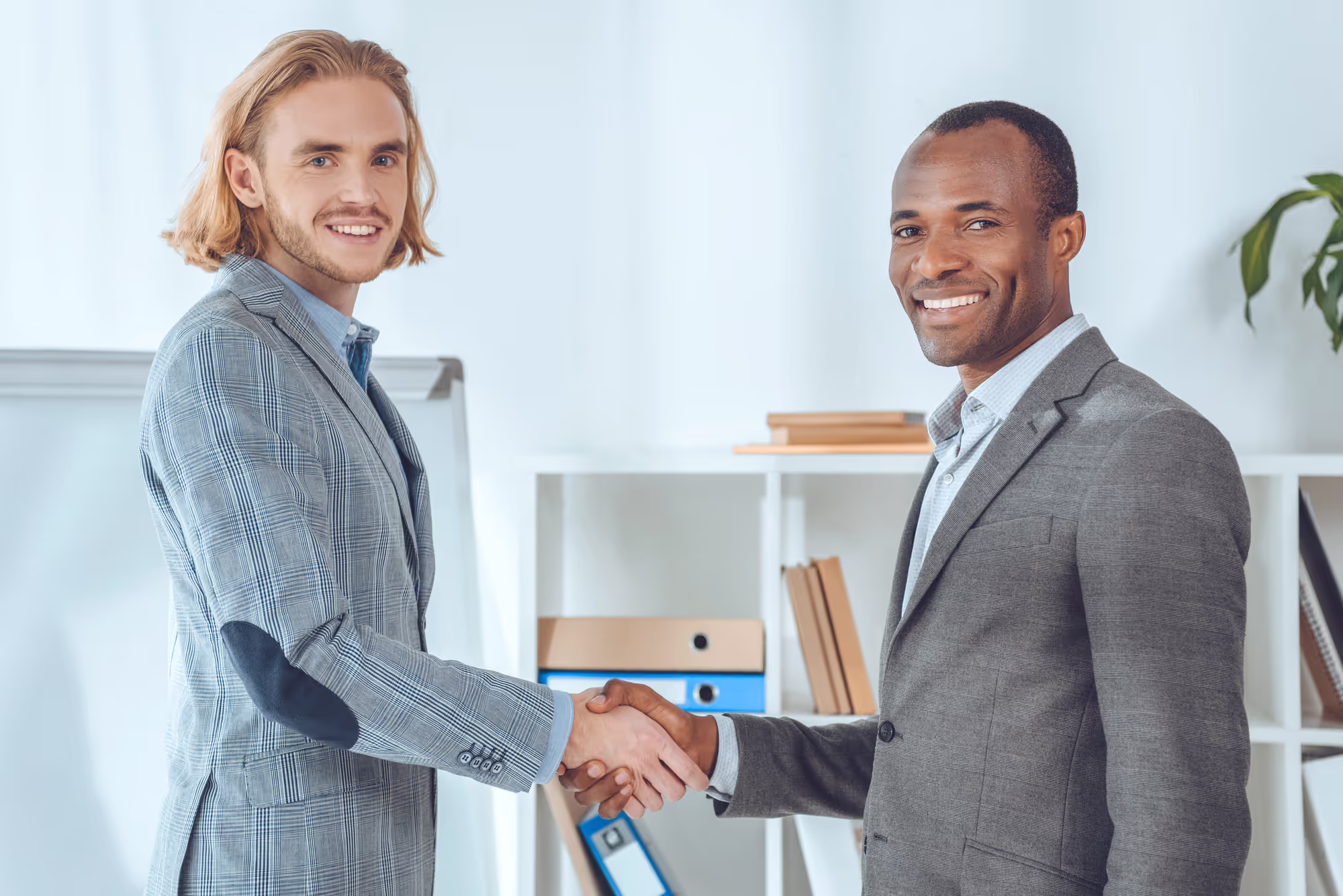 Two businessmen shaking hands at office space