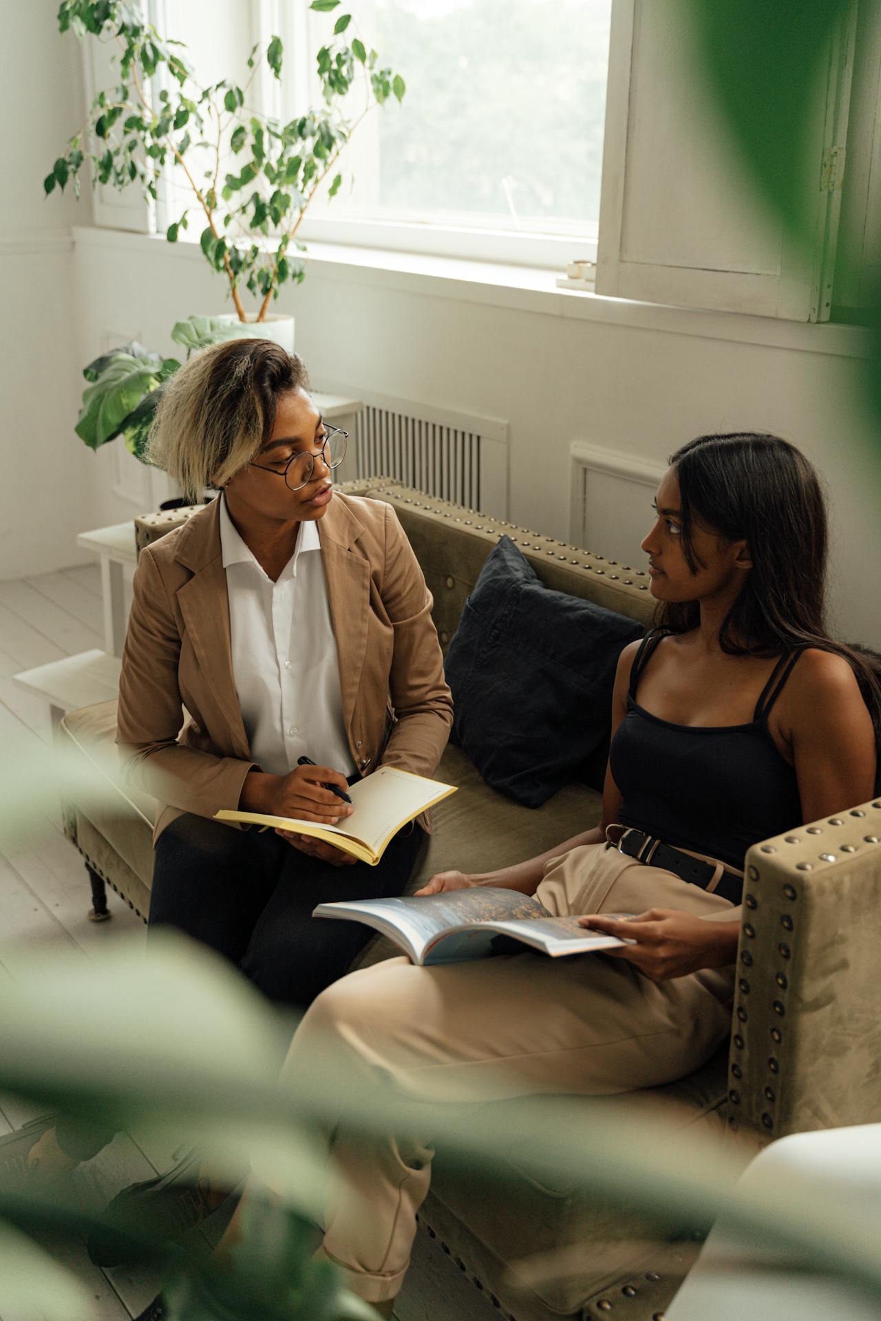 College Student Counseling Session on Sofa College student talking to a mental health counselor while sitting comfortably on a sofa, highlighting the importance of supporting college student mental health from distance.