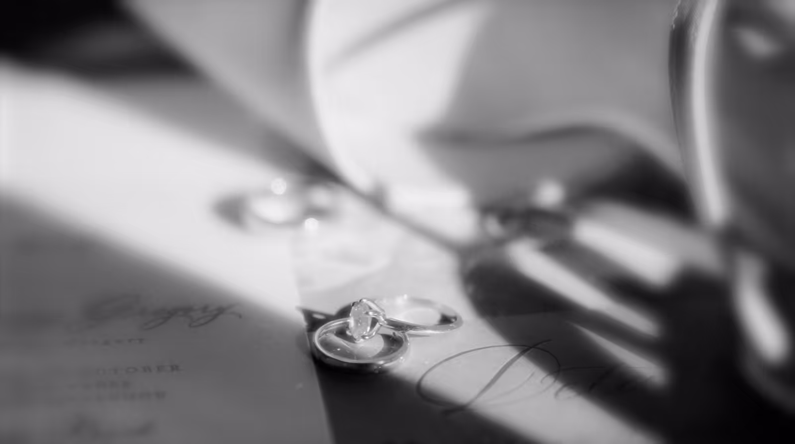 Close-up of elegant wedding rings resting on a vintage book with soft, romantic lighting.