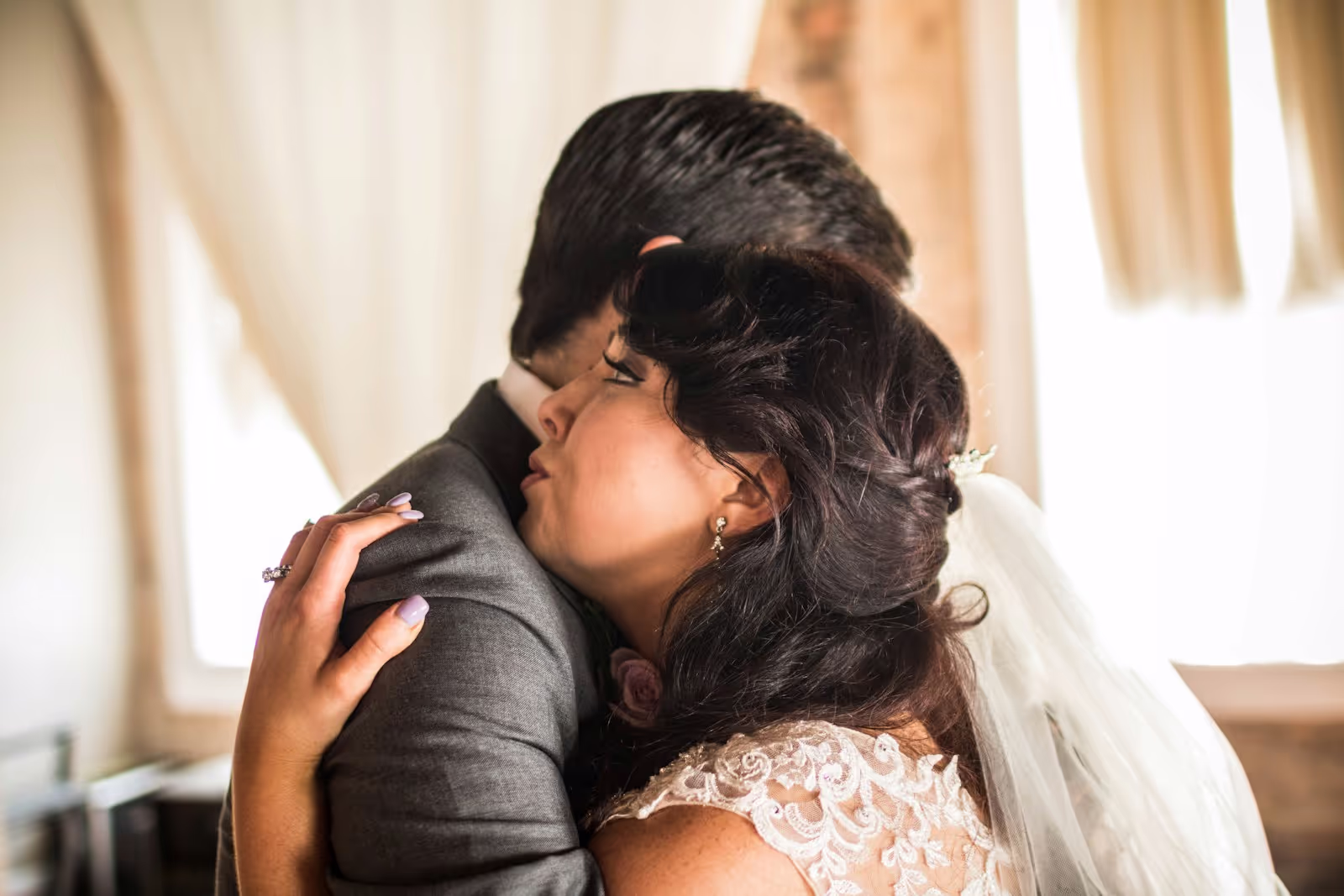 A wedding couple sharing a tender moment, embracing softly in natural light.