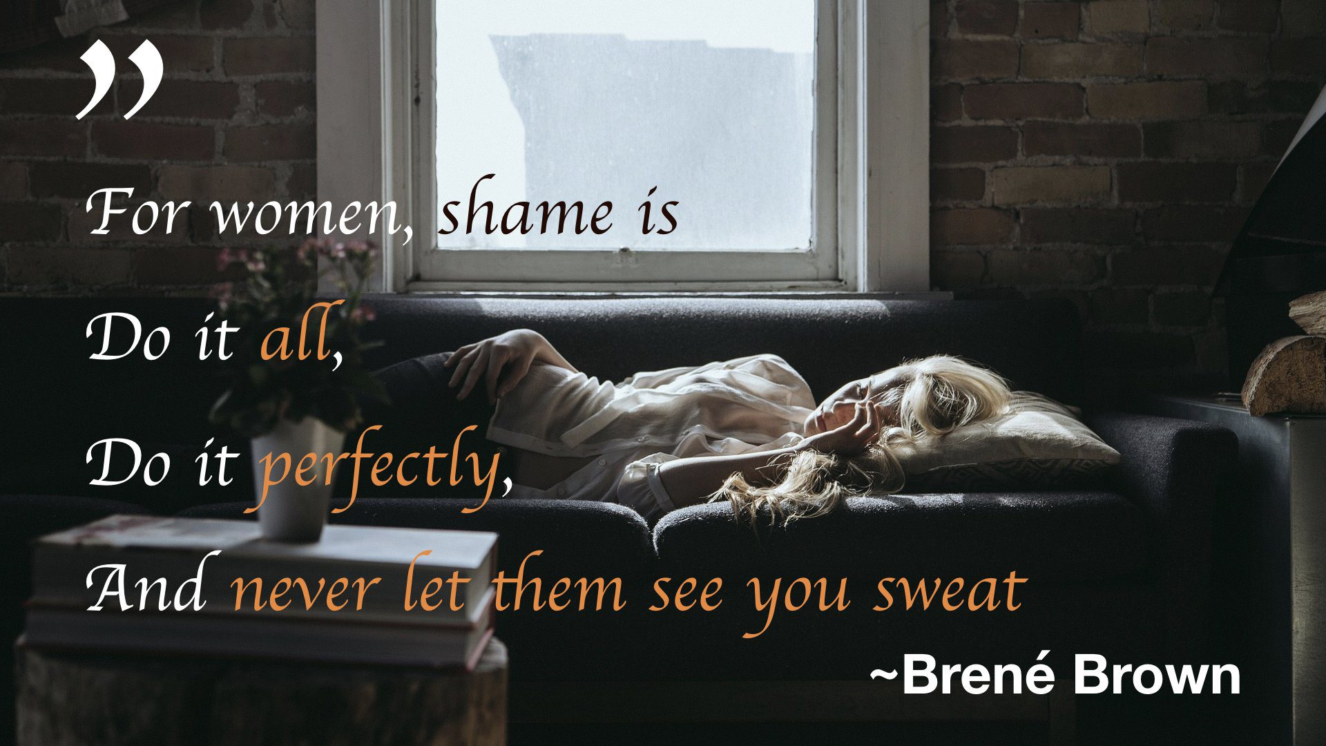 A woman lying on a dark couch in a dim brick-walled room beneath a window, with overlaid quote text: For women, shame is Do it all, Do it perfectly, And never let them see you sweat - Brené Brown.