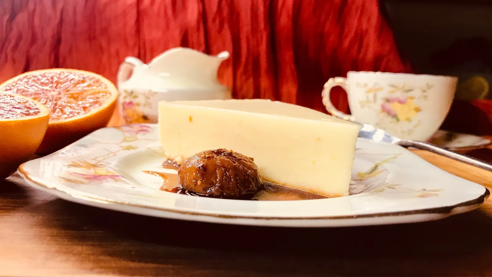 A jar of homemade rose-scented fig compote beside fresh figs on a rustic surface