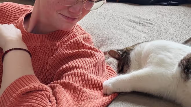 A cat grabbing Caro by her Jumper