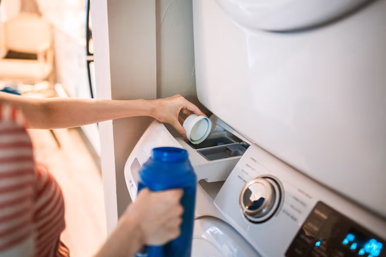 A person pouring washing liquid into the washing machine A person pouring washing liquid into the washing machine