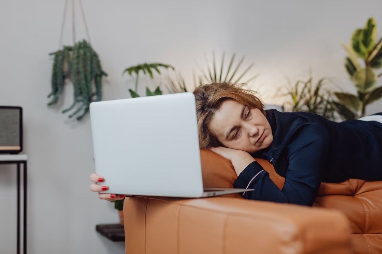 A person that is tired laying on a couch, with no motivation A person that is tired laying on a couch, with no motivation