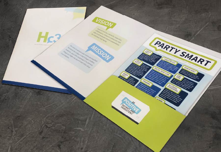 An open white and green folder or brochure titled 'PARTY SMART' on a dark grey surface. The left side of the folder displays a green and blue logo 'Hc3', and sections for 'VISION' and 'MISSION' with text. The right side contains a grid of advice under the 'PARTY SMART' heading, including topics like 'CHECK FIRST', 'COMMUNICATE', 'SOBER HOST', 'HOUSE RULES', 'SOCIAL HOST LAW', 'END TIME', 'INSIDE ONLY', 'TRAINING', and 'ALCOHOL POISONING'. The bottom right pocket of the folder is green and holds a white card with the text 'BE POSITIVE, PATIENT, AND PERSISTENT.'